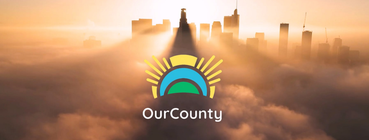 A photo of a city skyline above the clouds with the OurCounty logo overlayed on top 